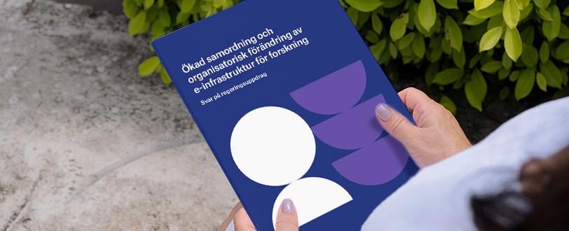 Kvinna som håller i rapporten "Ökad samordning och organisatorisk förändring av e-infrastruktur för forskning" av Vetenskapsrådet