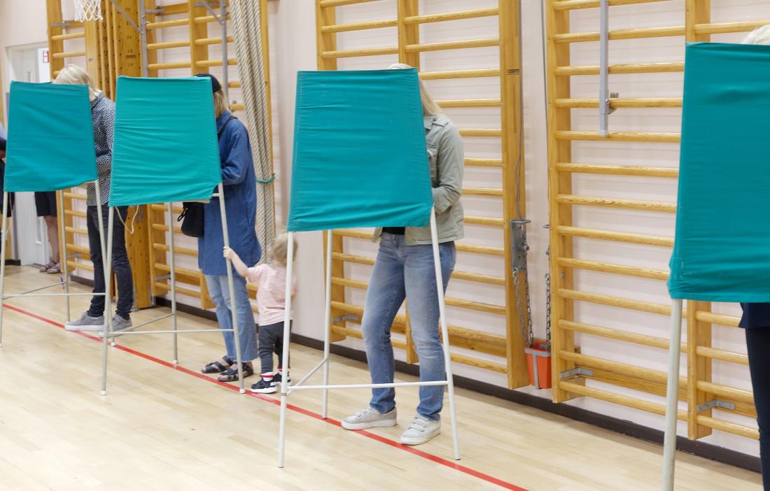 Väljare röstar bakom valskärmar. 